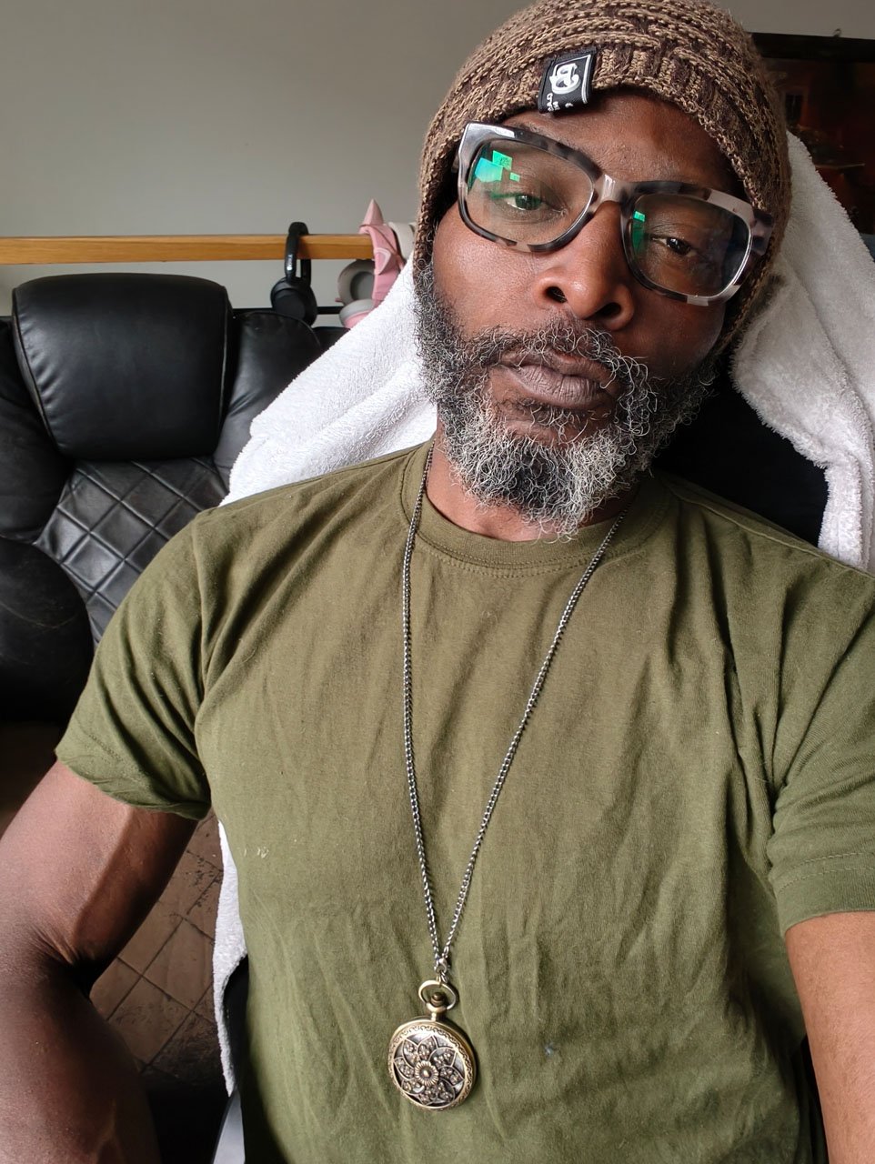 Selfie Portrait shot of African-American man with glasses wearing an olive t-shirt and a bronze pocket watch