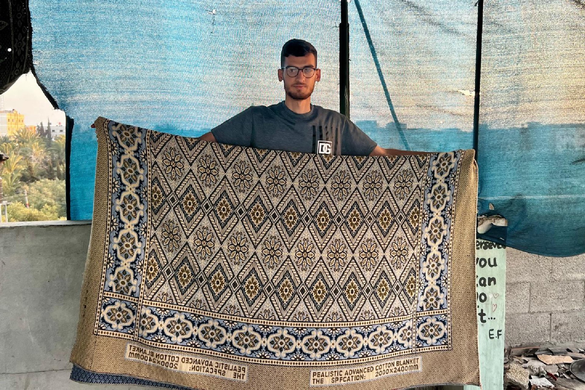 Saeed Ismail holding the blanket that started a controversy on Bluesky about whether he was AI generated.