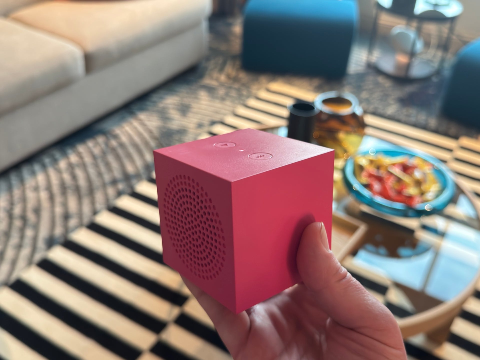 A hand holding a single red Kallsup speaker