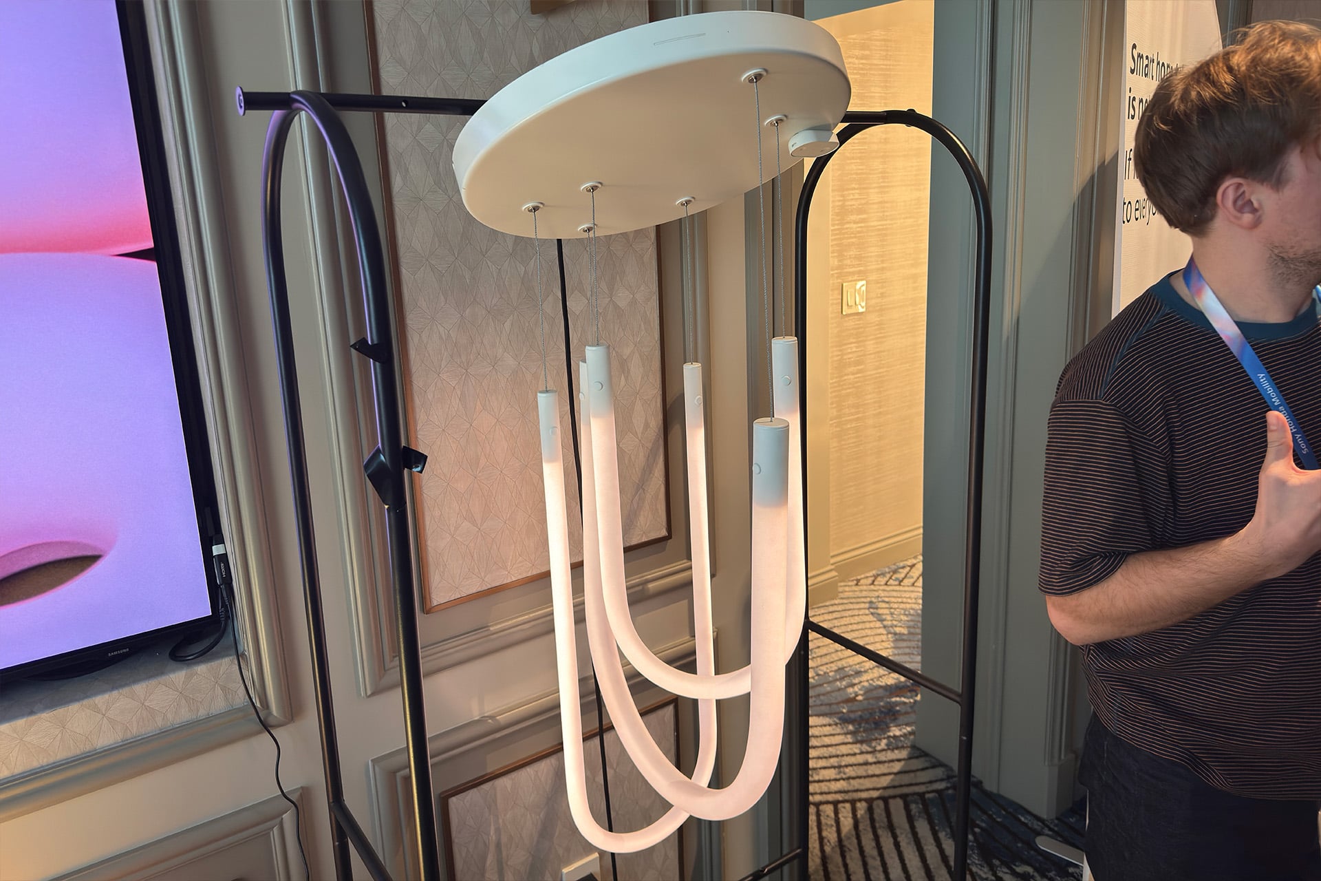 A Varmblixt pendant lamp, with three light tubes bent into a U shape and hanging from a flat circular ceiling mount.