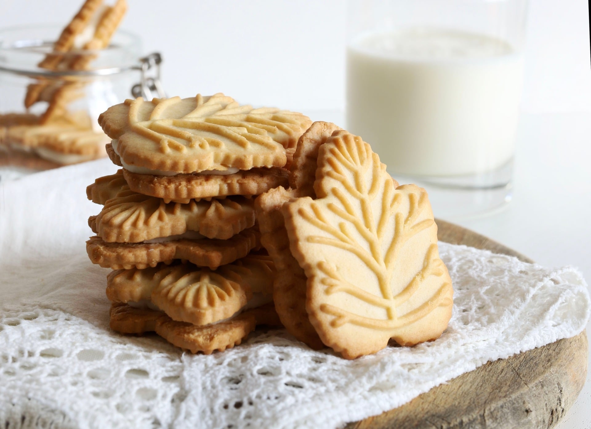 A stack of Canadian maple cream cookies on a plate with a glass of milk 