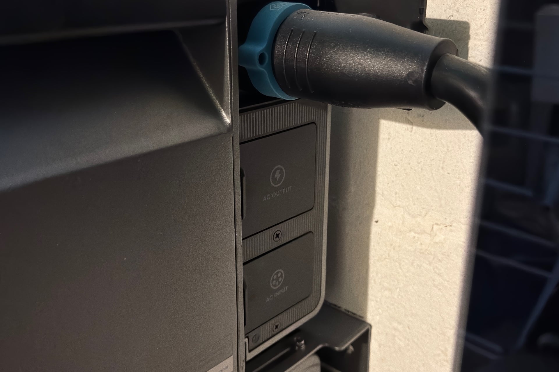Close-up of the side of the Solix E10, showing the power cable connecting it to the Power Dock, as well as AC outlet and inlet covers.
