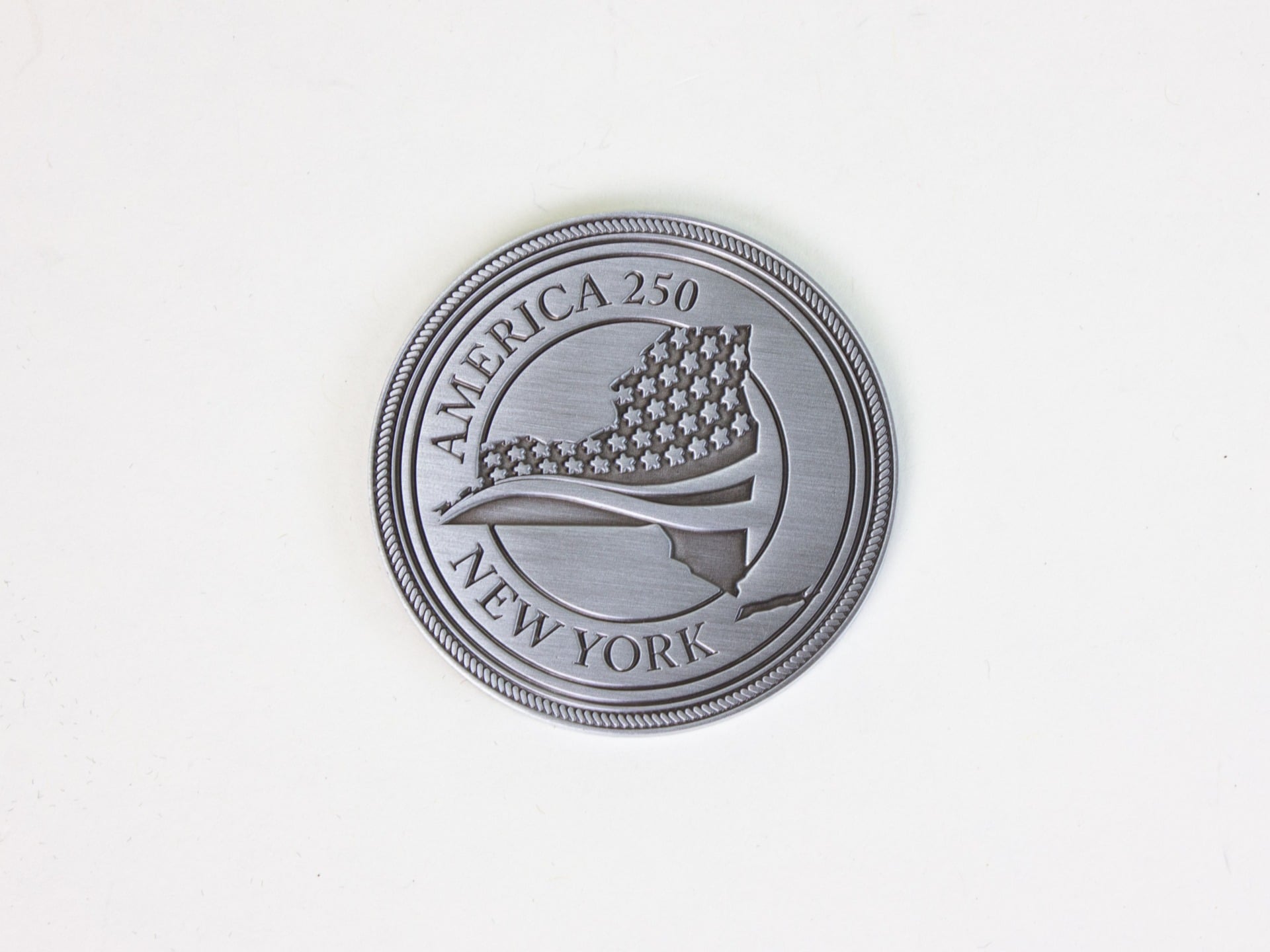 New York's contribution to the America 250 time capsule, which is a coin that reads “Kingston, NY 1777 New York’s First Capital” on the back.
