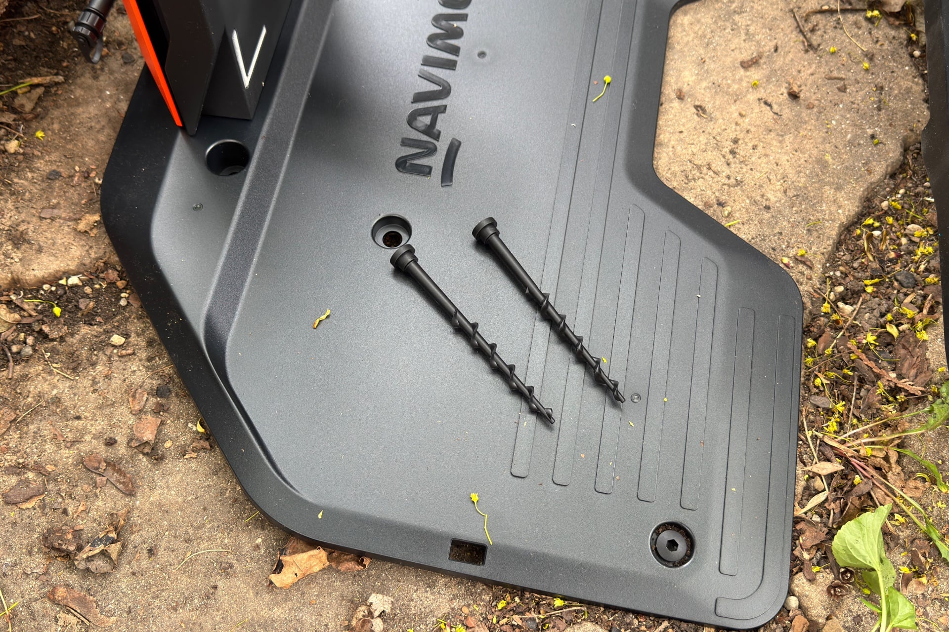 The Navimow dock's ground plate with two anchor screws resting on it.