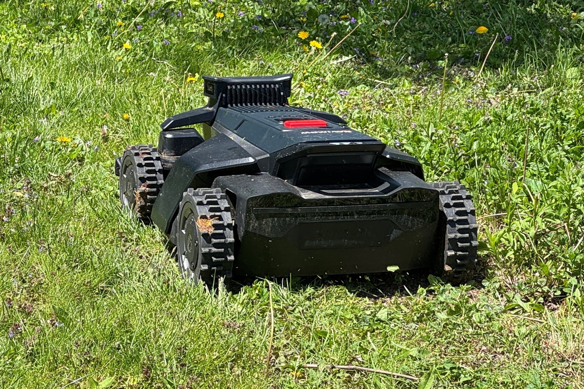 Navimow X430 pictured from behind, mowing through grass.