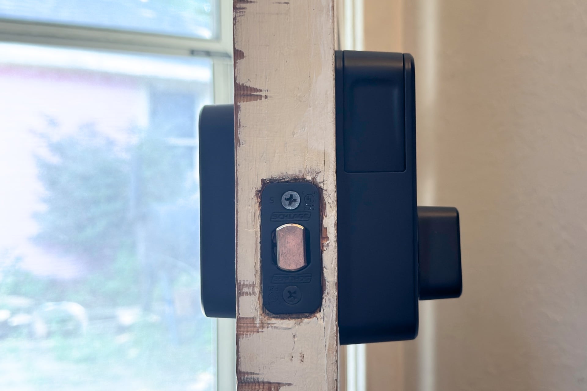 Schlage Sense Pro pictured from the edge, showing the deadbolt in the door, and the profile of the keypad and interior thumbturn portion. The interior part is much thicker and taller.