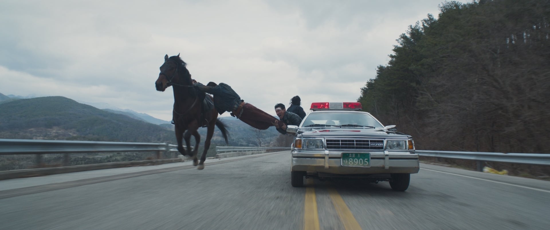 Hope still of a man climbing from a horse to a police car on a highway.