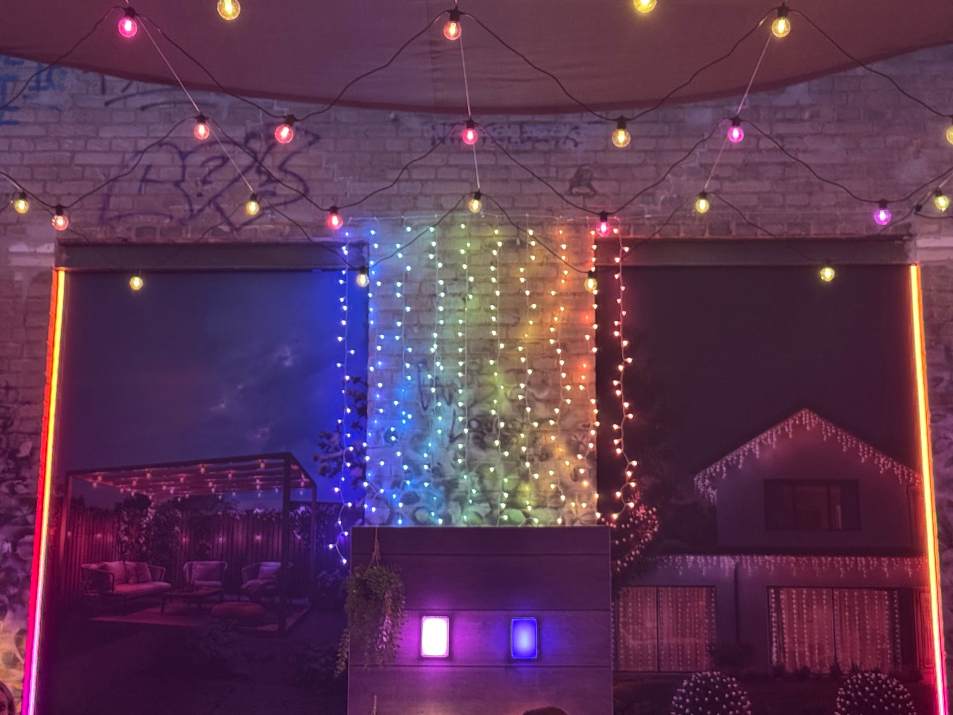 Picture showing a curtain light against a brick wall, displaying a rainbow gradient.