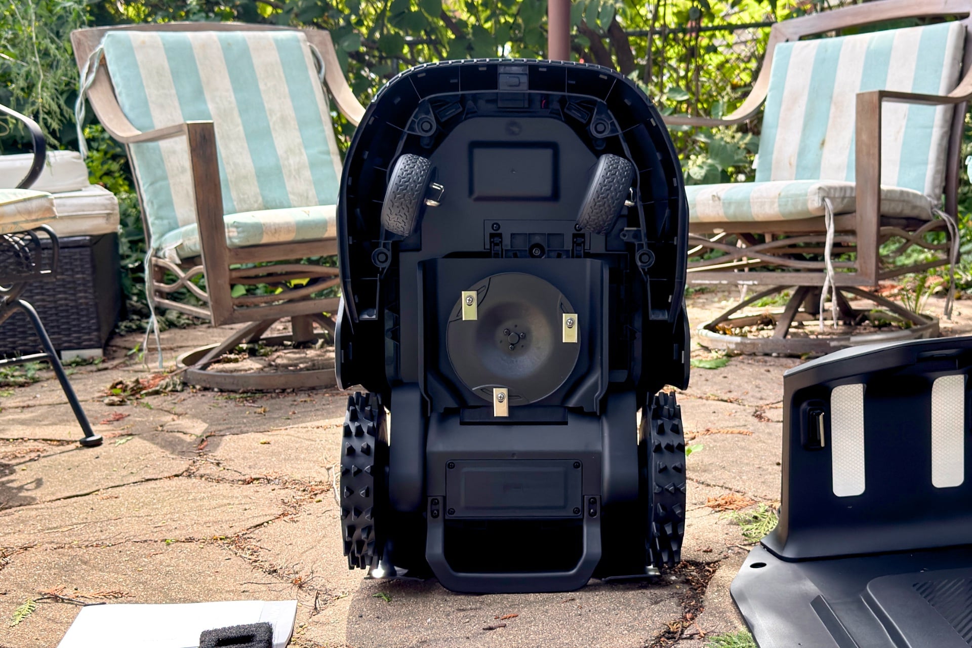 Zoomed-out image of the mower's undercarriage, showing its mowing disc, rear wheels, and caster-style front wheels.