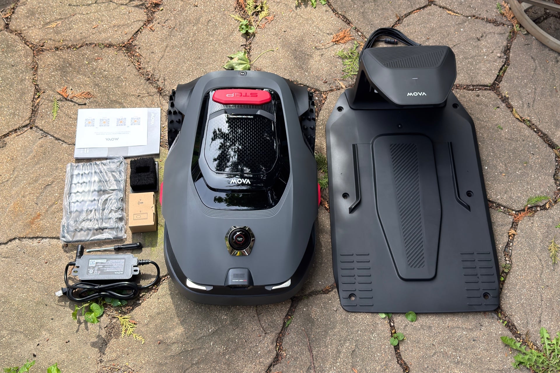 Photo from above showing the Mova Lidax Pro 800, its dock, a manual, stakes for securing the dock to the ground, power adapter, and other accessories